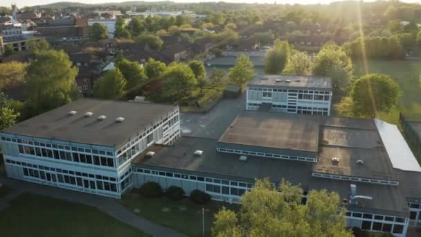 Flygdrönarvy som lyfter framför en generisk skolbyggnad under en sommarsolnedgång — Stockvideo