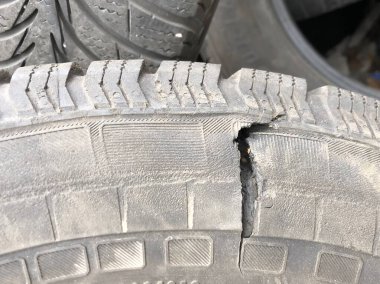 Eski bir araba lastiğinde delik. Yolcu arabasının lastiği aşınmış. Eski tekerleklerin çöplüğünde patlamış lastik..