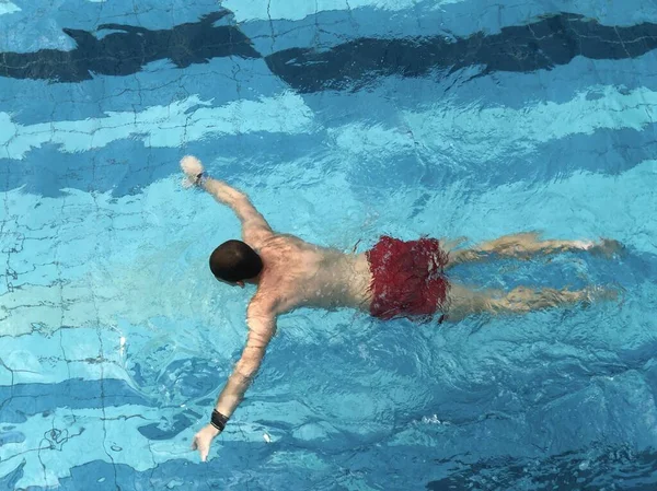 A man swims underwater in a sports pool.