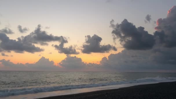 美丽的落日在海面上 从海滩上眺望 太阳光穿过云彩 夏日的傍晚 乌云密布的天空 地平线后面隐藏着太阳 — 图库视频影像