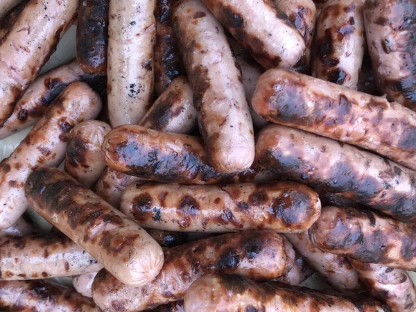 Textura de fondo: una pila de salchichas a la parrilla. Embutidos de pollo a la parrilla para un picnic. Cerdo y ternera en forma de embutidos . — Foto de Stock