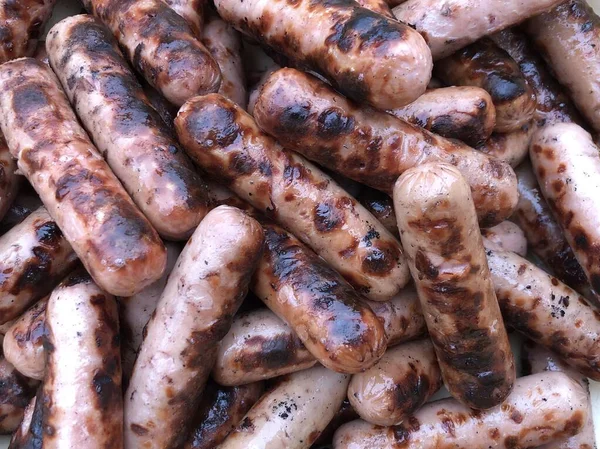 Textura de fondo: una pila de salchichas a la parrilla. Embutidos de pollo a la parrilla para un picnic. Cerdo y ternera en forma de embutidos . —  Fotos de Stock