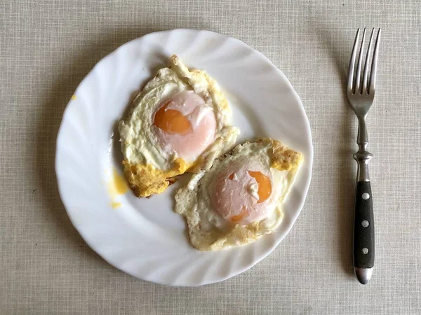 Stekta ägg i en vit tallrik, på ett grått bord. Stekta kycklingägg till frukost. Smakrik rätt med äggula. — Stockfoto