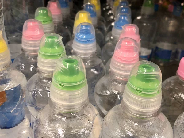 Много бутылок газированной воды. Фон текстуры: пластиковые бутылки с лимонадом. Бутылки с минеральной водой имеют яркие колпачки . — стоковое фото