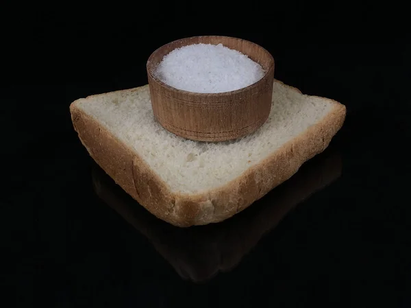 Crosta de pão e saleiro com sal sobre um fundo preto. Uma fatia de pão integral com sal branco, close-up. Conceito: sem fome — Fotografia de Stock
