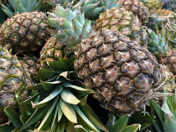 Background texture: ripe, delicious pineapples. Exotic fruits on a grocery store shelf. Pineapple season, harvesting. Concept: healthy diet, fruit diet, vitamins. — Stock Photo, Image