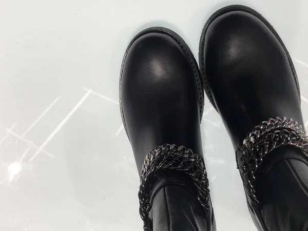 Negro, de moda, botas nuevas sobre un fondo blanco. Zapatos modernos para mujer en un estante de una zapatería. Un par de botas elegantes de mujer en una cadena . — Foto de Stock