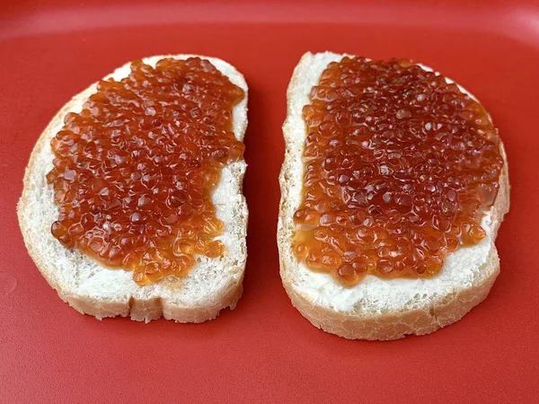 Sandwiches with red caviar, closeup. Bread with butter and fish caviar on a tray. Festive treat on the table. — Stock Photo, Image