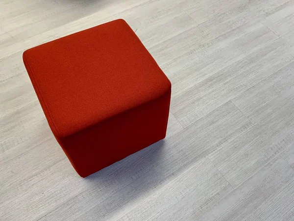 Червоний кубик на сірому фоні. Один м'який стілець на підлозі. Комфортні, домашні меблі . — стокове фото