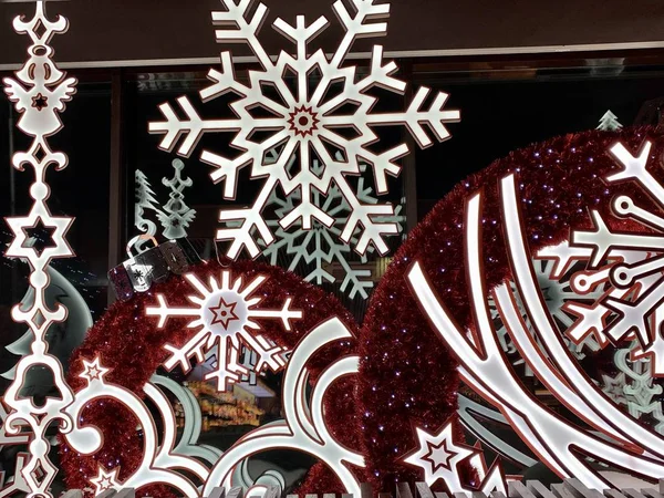 Los escaparates de Navidad en la tienda. Decoración festiva en las ventanas. Guirnaldas ardientes, copos de nieve decorativos. Textura de fondo: decoración con bombillas led . — Foto de Stock