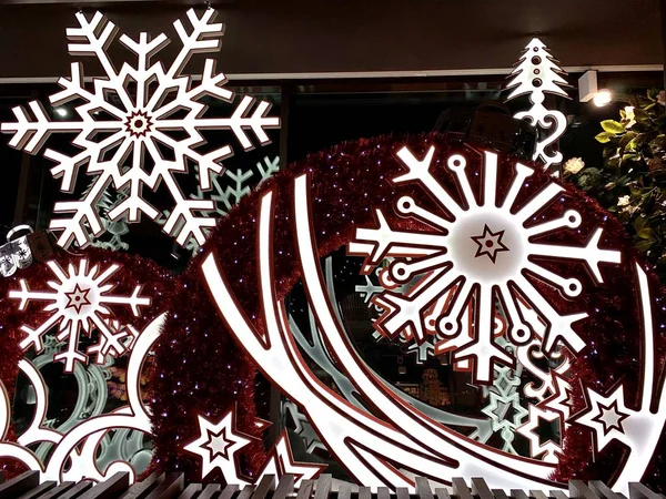 Okna świąteczne w sklepie. Świąteczne dekoracje na oknach. Płonące girlandy, ozdobne płatki śniegu. Konsystencja tła: dekoracja z żarówek LED. — Zdjęcie stockowe