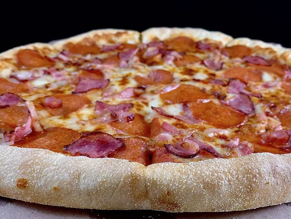 Pizza con salchicha y queso, primer plano sobre fondo negro. Textura de fondo: deliciosa pizza casera . — Foto de Stock