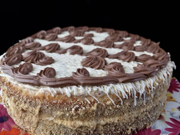 Round cake with cream patterns, on a black background. A sweet birthday present for a teenager. A festive dessert for the whole family. Baking with icing on a plate. — Stock Photo, Image