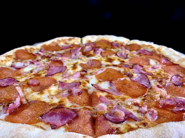 Pizza con salchicha y queso, primer plano sobre fondo negro. Textura de fondo: deliciosa pizza casera . — Foto de Stock
