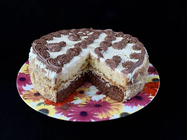 Round cake with cream patterns, on a black background. A sweet birthday present for a teenager. A festive dessert for the whole family. Baking with icing on a plate. — Stock Photo, Image