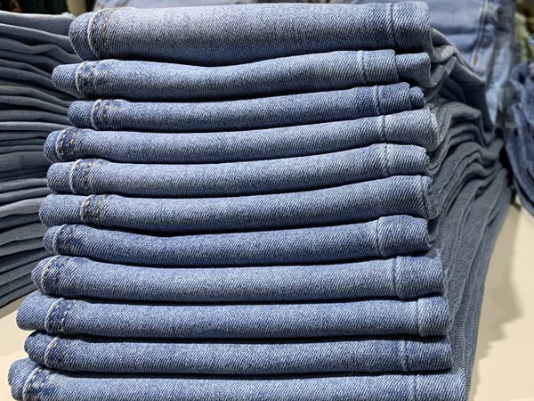 Montones de vaqueros modernos de diferentes tamaños. Una selección de jeans en una tienda de ropa. Estantes con ropa en el departamento de productos de algodón . — Foto de Stock