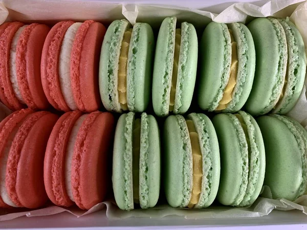 Multicolored tasty macarons on a black background. Colorful french macarons of various tastes, top view. Original dessert, homemade cakes. — 스톡 사진