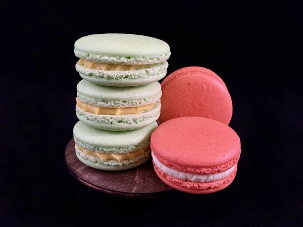 Macarons saborosos multicoloridos em um fundo preto. Macarons franceses coloridos de vários gostos, vista superior. Sobremesa original, bolos caseiros . — Fotografia de Stock