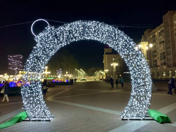 新年的拱门在晚上的城市街道上。 冬季博览会期间的圣诞装饰. — 图库照片