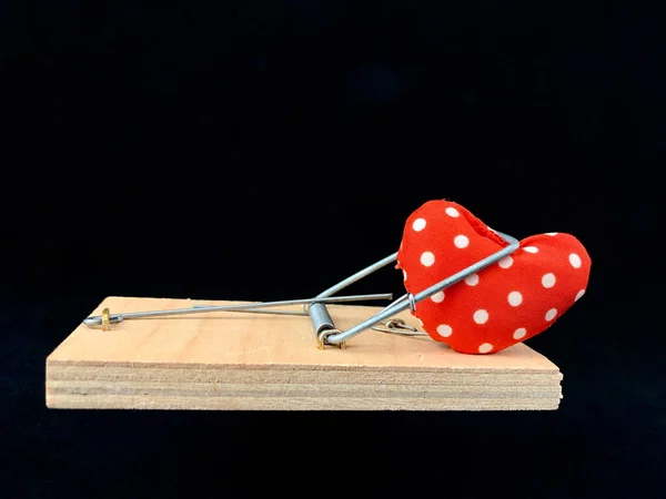 Hart in een muizenval op een zwarte achtergrond. Een val met een hart, Liefde is als aas. Valentijnsdag, liefdesdag — Stockfoto