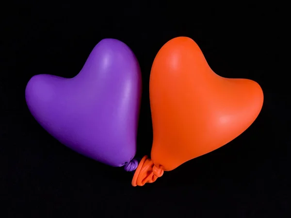Heldere ballonnen in de vorm van een hart, op een zwarte achtergrond. Twee kleurrijke rubberen hartjes. Concept: liefde voor twee, samen voor altijd, eenheid. — Stockfoto