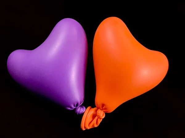 Heldere ballonnen in de vorm van een hart, op een zwarte achtergrond. Twee kleurrijke rubberen hartjes. Concept: liefde voor twee, samen voor altijd, eenheid. — Stockfoto