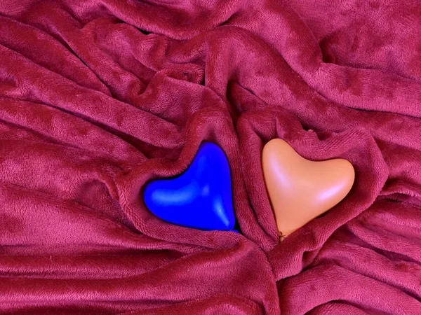 Cuori multicolori su tessuto morbido. Due cuori su una coperta rossa. Concetto: giorno di San Valentino, amore — Foto Stock