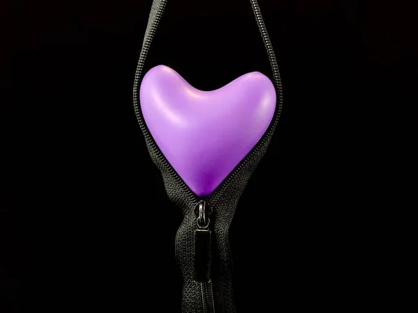 Heldere ballon in de vorm van een hart, op een zwarte achtergrond. Kleurrijk rubberen hart in een rits. Concept: open liefde, openheid. — Stockfoto