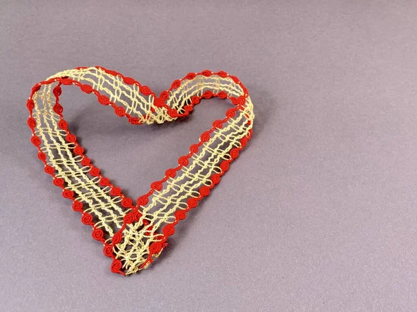 Cuore realizzato in nastro con pizzo, sfondo isolato. Forma del cuore fatta di nastro decorativo con motivi. Elemento per biglietto da visita, San Valentino, invito di nozze . — Foto Stock