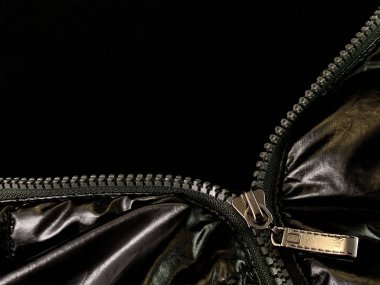 Background texture: zipper in a jacket on a black background. Opened lock on knit fabric.