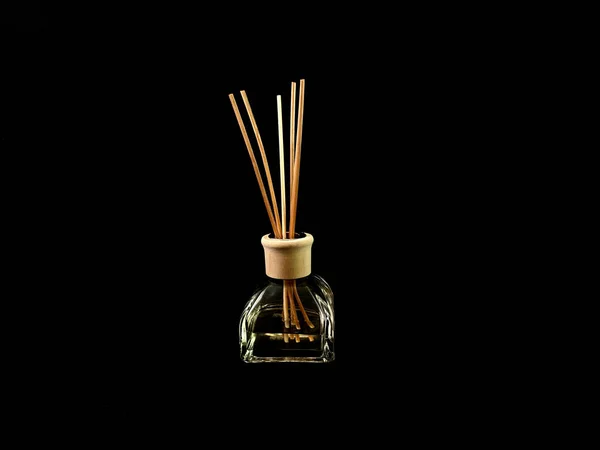 Lufterfrischer auf schwarzem Hintergrund. Räucherstäbchen in einem Behälter mit Parfüm. Aromatherapie-Stöcke in einer Glasflasche mit Öl — Stockfoto