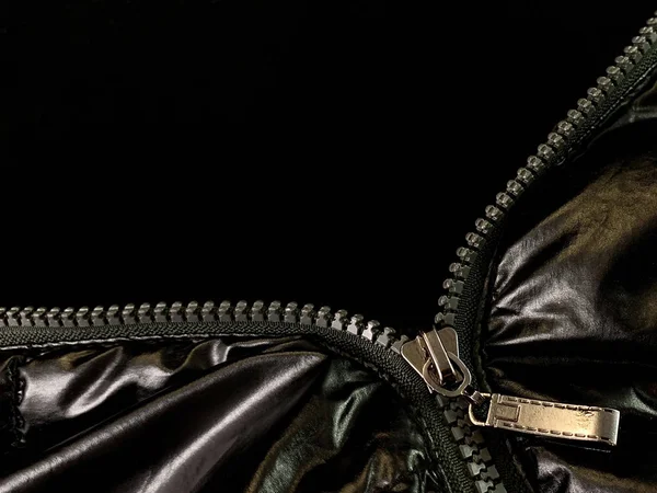 Background texture: zipper in a jacket on a black background. Opened lock on knit fabric.