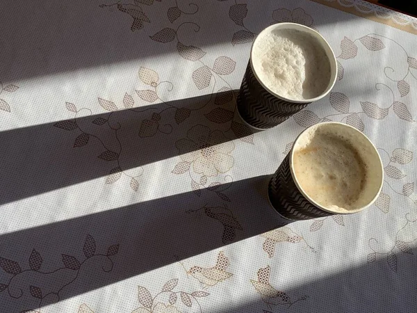 Disposable paper cup with cappuccino and shadow on the table. A serving ...