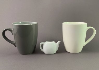 Gri arka planda iki fincan ve küçük bir çaydanlık. Çay ya da kahve için koyu ve açık kahve bardağı. Konsept: Aşk, iki kişilik çay, Sevgililer Günü.