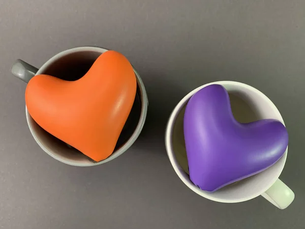 Twee veelkleurige harten in een beker. Mok met een hart van binnen, op een zwarte achtergrond. Concept: liefde, thee voor twee, Valentijnsdag. — Stockfoto