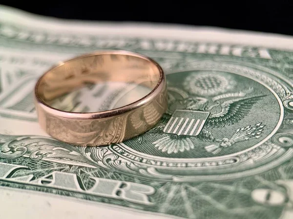 Inelul de nuntă se află pe o bancnotă de dolari. Inel de aur pe dolari americani. Conceptul: căsătoria de confort . — Fotografie, imagine de stoc