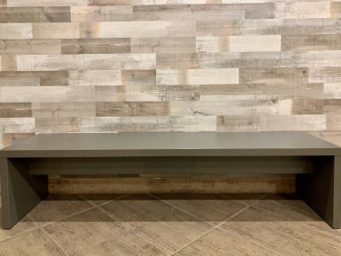 Duvarın arkasında gri bir bank var. Birkaç kişi için ahşap koltuk. Kurumun koridorunda bekleyecek bir yer..