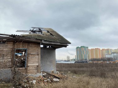 Yeni bir binanın arka planındaki eski harabe ev. Kapısı ve penceresi olmayan, çatısı kırık terk edilmiş bir ev. Konsept: yıkım, inşaat