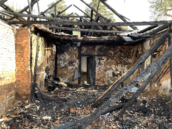 Old destroyed house after a fire against the sky. Abandoned house with no doors and windows with a broken roof. Concept: devastation, desolation