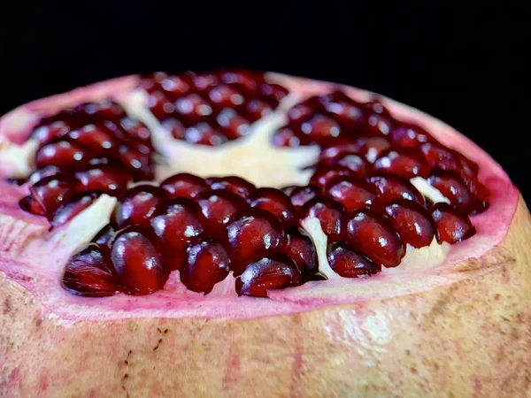 Granada jugosa y pelada sobre un fondo negro. Frutas de granada grandes y maduras. Concepto: dieta de frutas, jugo de granada, vitaminas —  Fotos de Stock