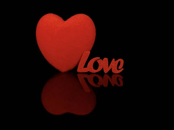 Η επιγραφή "Αγάπη" και μια κόκκινη καρδιά σε μαύρο φόντο. Αντανάκλαση δύο καρδιών από μια γυαλιστερή επιφάνεια. Η έννοια του Αγίου Βαλεντίνου, γάμοι και άλλες διακοπές. — Φωτογραφία Αρχείου