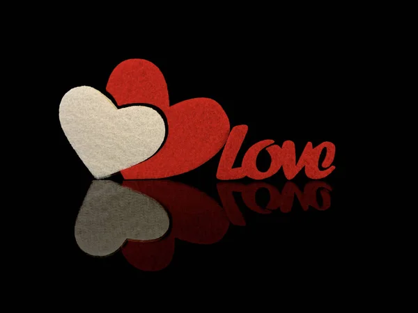A inscrição "Amor" e um coração vermelho sobre um fundo preto. Reflexão de dois corações de uma superfície brilhante. O conceito de Dia dos Namorados, casamentos e outros feriados . — Fotografia de Stock