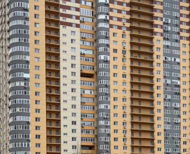 Arka plan dokusu: çok katlı yeni ev. Yeni bir bölgede sarı-gri bir bina. Konsept: Gayrimenkul yatırımı, ipotek, yeni bina.