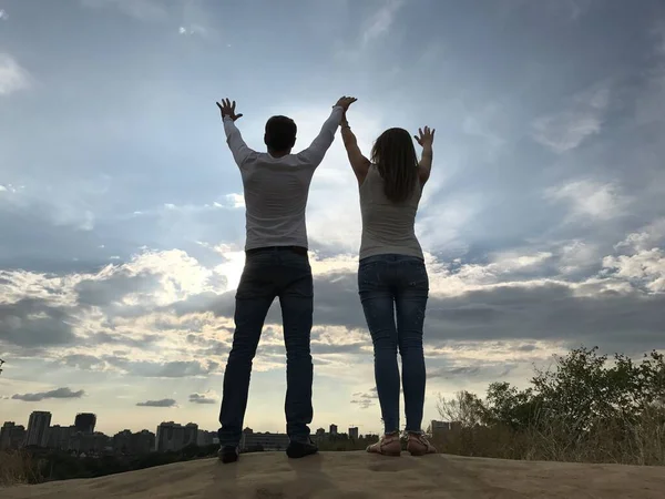 Een man en een meisje steken hun handen op naar de hemel. Twee geliefden staan samen en kijken in de verte. — Stockfoto