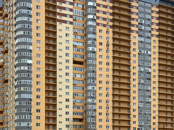 Hintergrund: mehrstöckiges neues Haus. hohes gelb-graues Gebäude in einem neuen Bereich. Konzept: Immobilieninvestitionen, Hypothek, Neubau. — Stockfoto