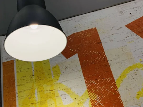 Struttura di sfondo: lampada su uno sfondo di parete giallo-arancio. Riflettori puntati su un muro di mattoni dipinti. Concetto: illuminazione d'interni, interni — Foto Stock