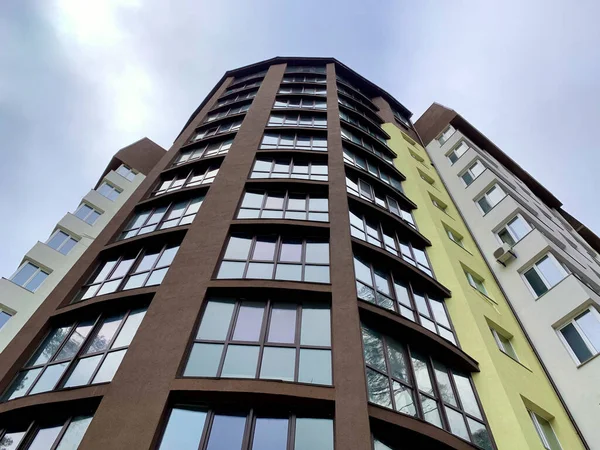 Edifício de vários andares em um fundo de céu azul. Edifício alto com janelas espelhadas, vista inferior . — Fotografia de Stock