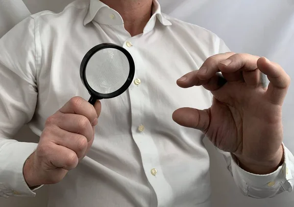 A person has a magnifying glass in his hands. A man holds a magnifier with his fingers. Concept: research — Stock Photo, Image