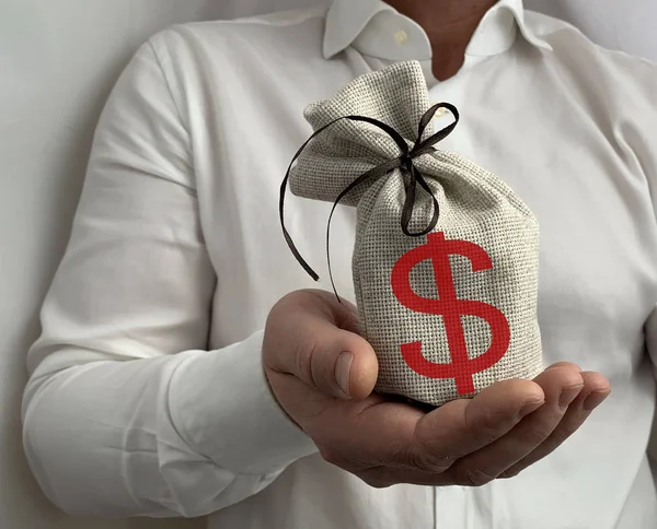 A bag with a dollar sign in the hand of a businessman. A man holds a burlap in his hands. A business man shows a sign of wealth. Concept: investment, material success — Stock Photo, Image