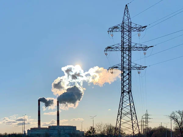 Smoke from industrial chimneys against a sunny, blue sky. Smoke from factory chimneys in an urban environment. Concept: environmental pollution, ecology.